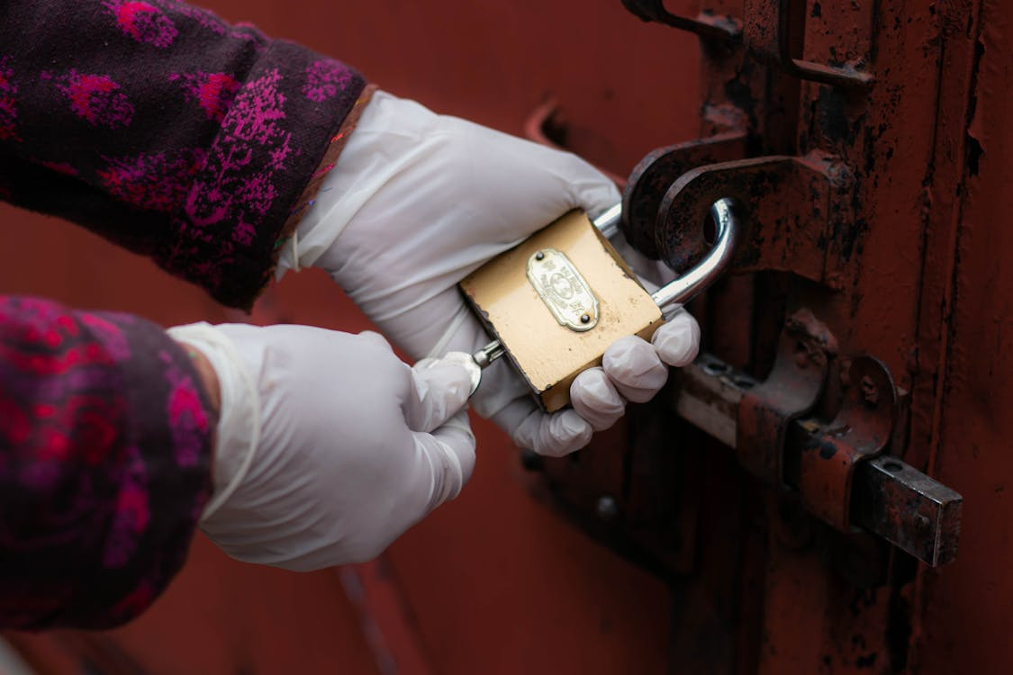 A person opening a gold padlock with a key 
